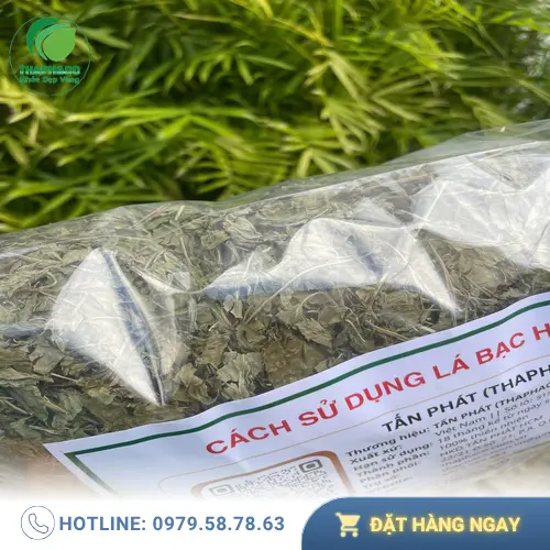 Một tách trà bạc hà nóng hổi, bốc khói nhẹ, đặt trên bàn gỗ, cạnh đó là những lá bạc hà tươi và một thìa mật ong.